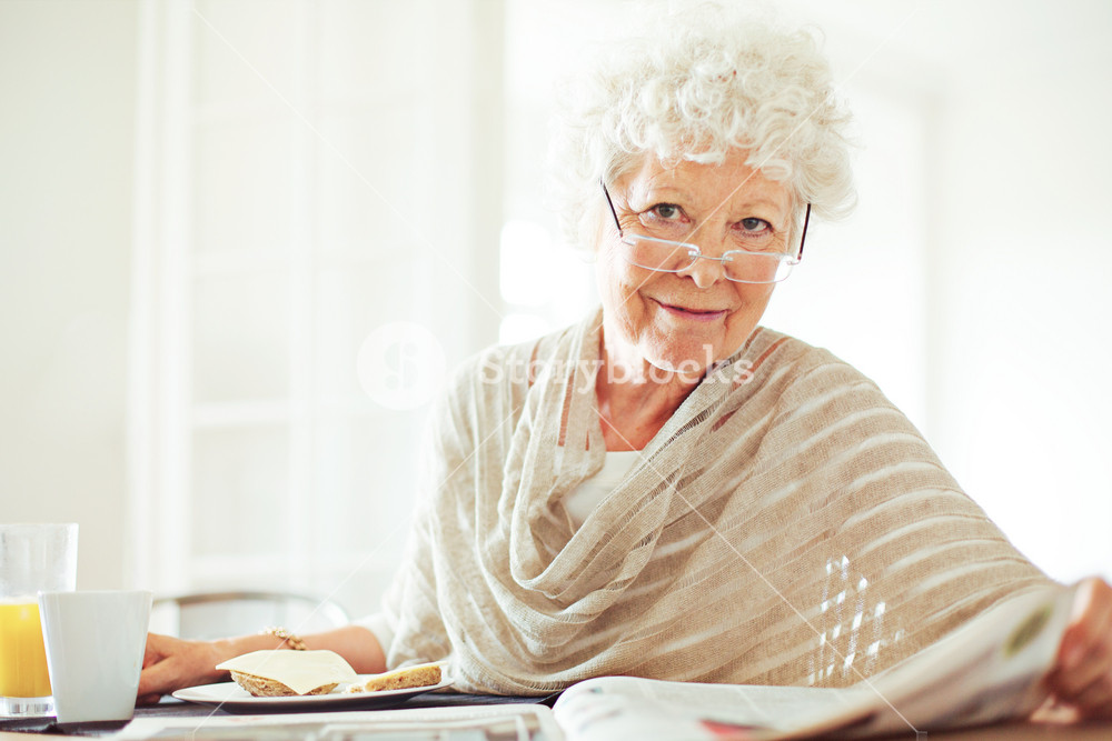 Happy senior woman reading her morning newspaper