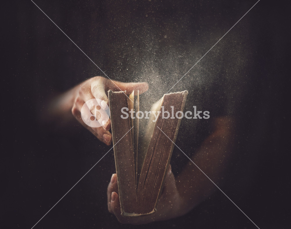 Holding an open book with dust coming out.