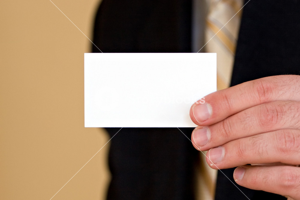 Macro shot of a man holding a business card up.  Plenty of copyspace for your logo or design.