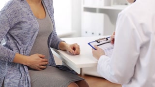 pregnancy, gynecology, medicine, health care and people concept - gynecologist doctor with clipboard and pregnant woman meeting at hospital