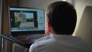 A man looks at advertisements for the sale or rental of housing on a laptop.