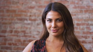 Portrait Of Smiling Hispanic Woman Standing Against Brick Wall In Coffee Shop