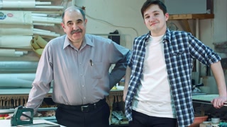 Portrait of two workers, standing in workshop, smiling and looking at camera